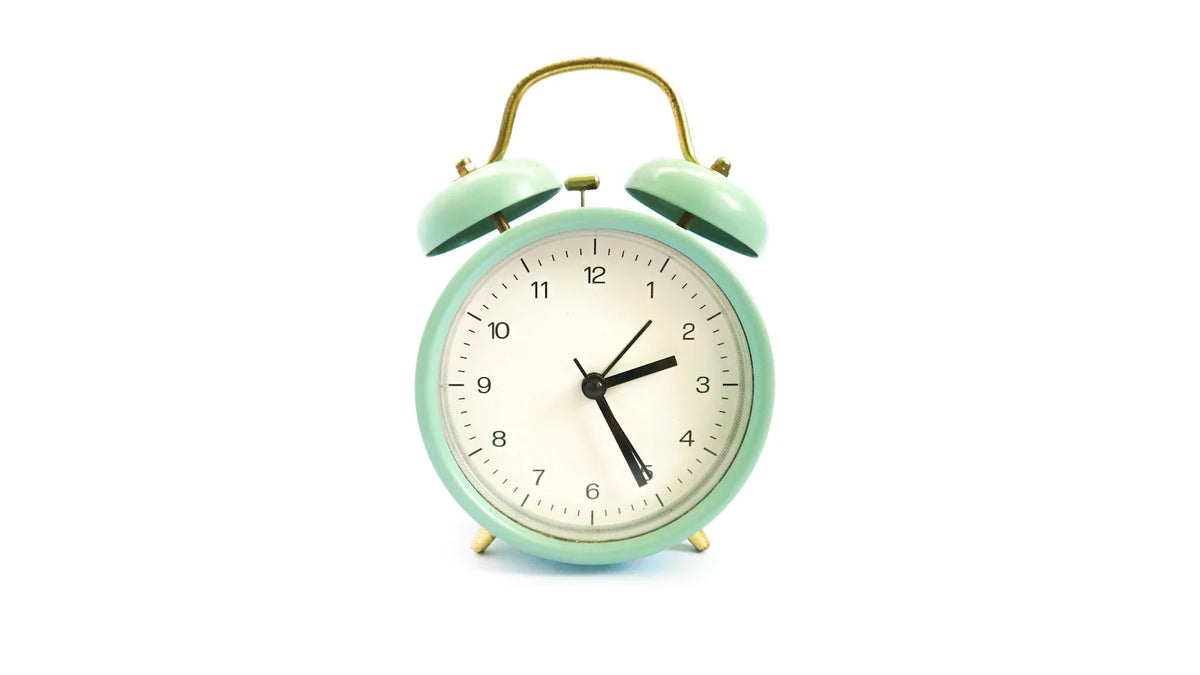 A green and white alarm clock. Photo: Abdul Artega on Unsplash
